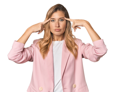 Young blonde in stylish pink suit focused on a task, keeping forefingers pointing head.