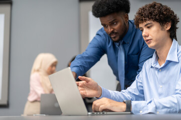 Diverse tech team meeting on software project, mentor guiding coworker on laptop, teamwork development using collaboration tools, modern technology, app design, dev training and enterprise SaaS team