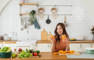 Asian woman hold orange juice in kitchen preparing healthy drink with blender, healthy lifestyle...