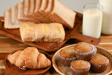 A loaf of freshly baked bread with slices, accompanied by a glass of milk on a wooden table, illuminated by warm sunlight in a cozy, rustic kitchen