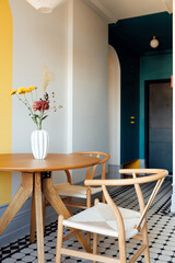 Modern design of rooms. A stylish dining room with a round wooden table and comfortable chairs made of natural materials.