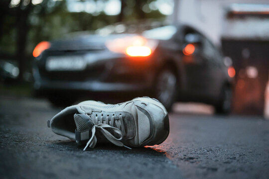 Shoe on the road with car in background after car accident.