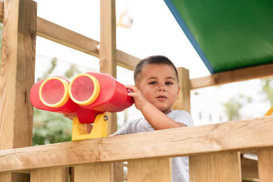Curious child exploring with binoculars in playground playhouse
