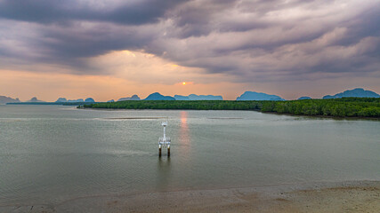 Aerial view of Rising at the entrance of a deep water channel flanked by mangrove forests, the lighthouse serves as both a navigation aid and a symbol of safety for the fishing community.