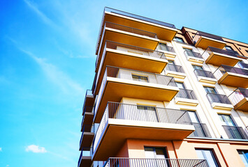 Fototapeta premium Balconies on blue sky, view up. New Apartment facade. Modern residential facade with balcony, windows. Architecture building exterior, house block. High Rise facade background. Modern housing estate.
