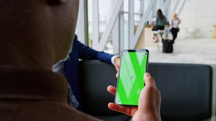 Over the shoulder shot of male passenger in airport departure lounge looking at green screen mobile phone - shot in slow motion - Powered by Adobe