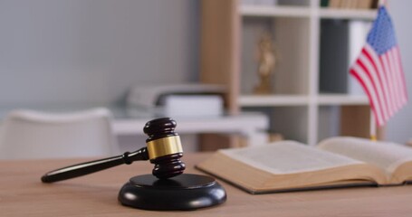 Close up of judge's gavel on workplace with USA flag in background. Empty interior of courtroom or lawyer office. Jurisdiction, legal law and justice concept. 4k video. Slow motion video. - Powered by Adobe