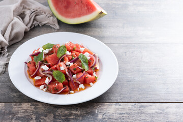 Fresh Watermelon Feta Salad with Mint and Red Onion on wooden table. Copy space