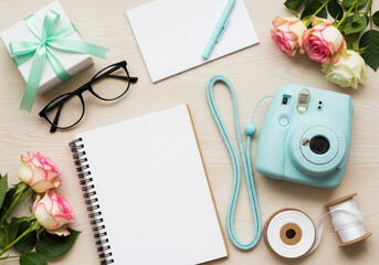 Flatlay composition with a pastel camera flowers notebook gift glasses and ribbon