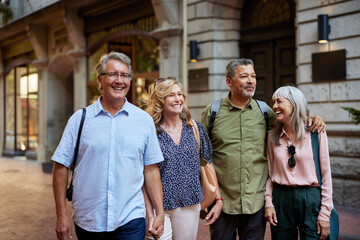 Senior multierthnic happy friends walking together in a city street