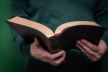 Person reading open bible in quiet moment of devotion. Hands holding and reading an open bible, spiritual connection with sacred scripture