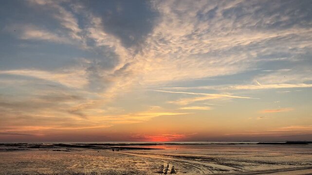 Time-lapse of a sunset over a beach at low tide near La Rochelle in France 