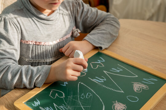 Preschool child draws letters, hearts, develops handwriting, fine motor skills, learning, early education, blackboard using, Early childhood development