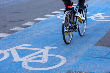 Blue bicycle lane with white signage and dynamic cyclist motion in Copenhagen, Denmark, expressing active commuting, sustainable urbanism and eco-conscious transportation habits