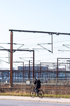 Commuter on bicycle passing train tracks in Copenhagen, Denmark, showing intermodal transport integration, everyday mobility and clean energy transit solutions in urban Europe