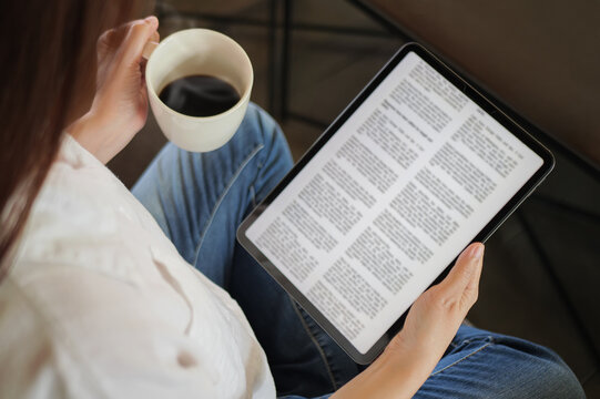 woman hand holding coffee cup and tablet, reading text on tablet device with a touchscreen interface for digital press article feed in the morning. mockup media publication website on portable tablet
