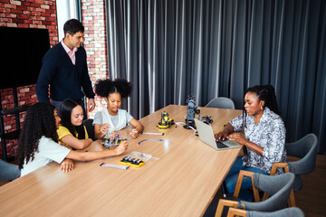 Children in a modern classroom explore robotics and electronics with teachers. Engaged in hands-on...