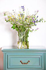 glass vase with wildflowers on the bedside table in the room