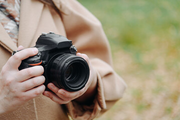 dslr camera in hands, young adult caucasian photographer woman in beige coat outdoors in autumn day, interesting hobby, amateur photography, creativity concept, copy space