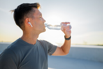 Man enjoying hydration while exercising outdoors during sunset