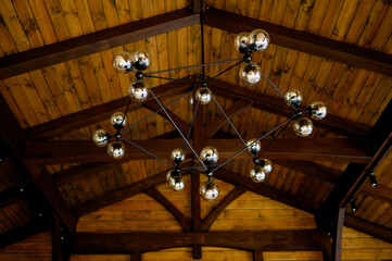 Pendant light with clear balls hanging from wooden ceiling.