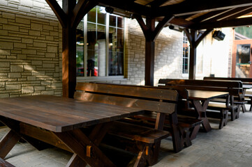 Wooden table and benches under a canopy, surrounded by greenery.