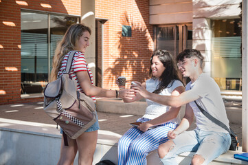 University students enjoying coffee and social interaction on campus while relaxing outdoors during a sunny day