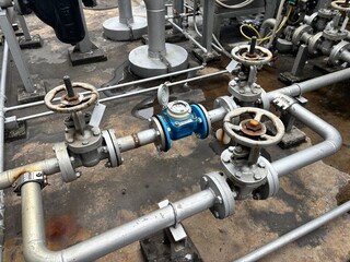 Industrial steel pipeline with manual wheel valves and a flow meter used for fluid distribution and...