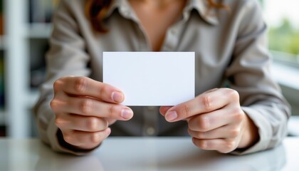 hands holding clean white business card on blurred background.
