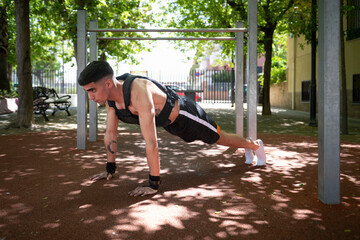 Young athlete doing calisthenics plank wearing weighted vest in park