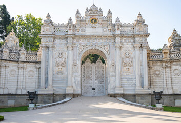 Obraz premium Dolmabahce Palace ornate gate under blue sky. Elaborate Ottoman palace or saray entrance architecture in Istanbul, Turkey. View from internal court. Decorations of buildings, gate, doorways and arches