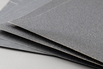 Close up sandpaper isolated on grey background. where the grains of sand on the sandpaper can be seen, and the difference level of rudenes on the sandpaper indicate the fineness of the grains of sand.
