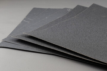 Close up sandpaper isolated on grey background. where the grains of sand on the sandpaper can be seen, and the difference level of rudenes on the sandpaper indicate the fineness of the grains of sand.
