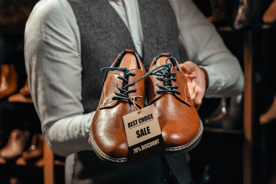 Salesman Holding Brown Leather Shoes with Discount Tag &ndash; 70% Off
