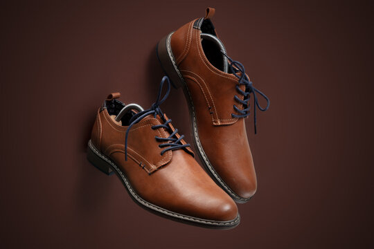 Elegant Brown Leather Dress Shoes with Laces on Brown Background