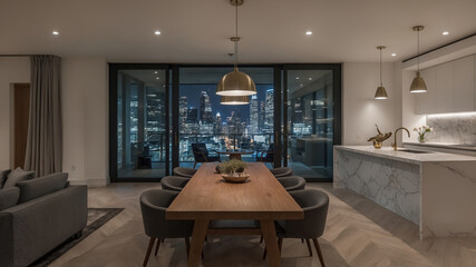 Luxury apartment interior featuring illuminated dining area kitchen and cityscape at night