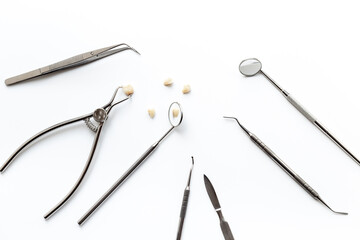 Many dental metal tools and teeth crows for implantation on white background. Professional Dentist desktop, top view