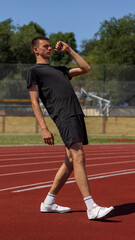 Obraz premium Athlete maintains balance on track beneath a sunny sky wearing casual sportswear. Concept of sportswear promo, posture detail, fitness clothing, active lifestyle and health-focused habits