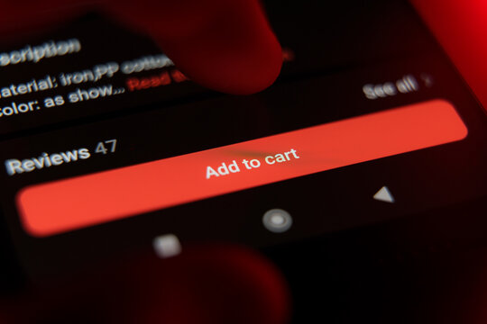 Close up of red Add to cart button on mobile shopping app with finger above screen.