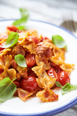 Farfalle pasta with cherry tomatoes, chicken breast and fresh basil. Close up.	