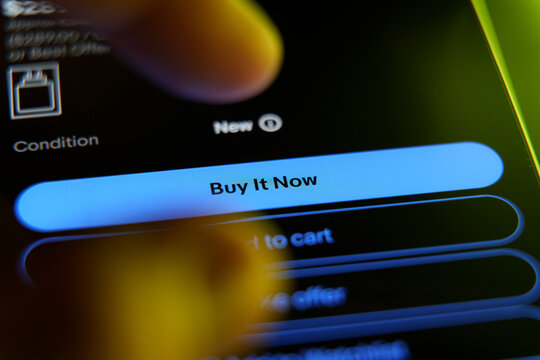 Closeup of a finger tapping the Buy It Now button on a smartphone screen during online shopping.