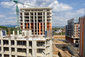 A multi-level concrete building is under construction with visible steel reinforcements
