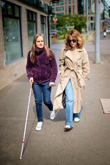 Visually impaired woman walking with her female friend in the city