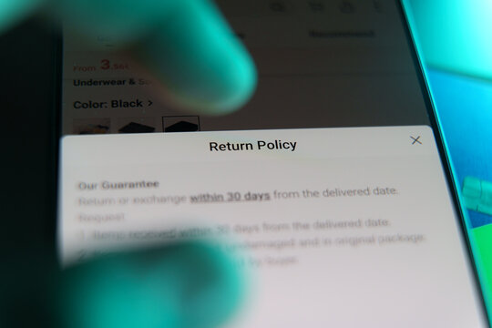 Smartphone screen showing online store return policy with finger pointing.