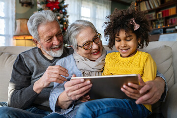 Portrait of a happy multigeneration family using electronic devices at home together
