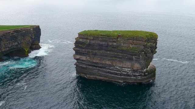 Aerial view of stunning Downpatrick Head coastal landmark with iconic Dun Briste sea stack. Dramatic cliffs and waves. Wild Atlantic Way Signature Discovery Point. Speed ramp effect.
