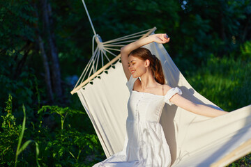 Young woman enjoying a moment of relaxation in a sunny garden, wearing a white dress, with a...