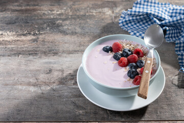 Healthy smoothie bowl with berries on wooden table. Copy space