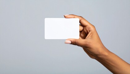 Obraz premium Mano de mujer sosteniendo una tarjeta blanca sobre fondo gris