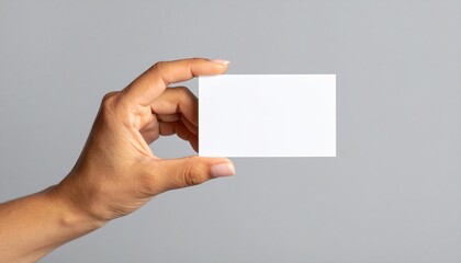 Mano de mujer sosteniendo una tarjeta blanca sobre fondo gris